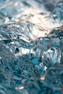 Close-up shot showcasing intricate, translucent ice formations on Diamond Beach, Iceland. Captures
