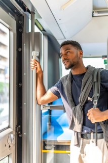 Vertical photo of a casual african businessman on the public bus on the way to work in the morning