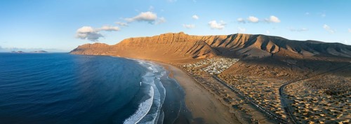 Panorama, Risco de Famara cliffs and sea with Famara beach, in the evening light, Playa de Famara,