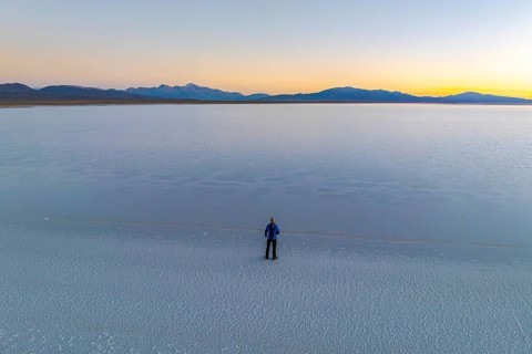 A lone figure stands on the expansive salt flats of Salinas Grandes in Salta, Argentina, as the sun