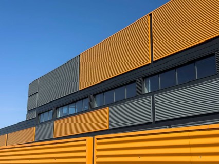 A striking modern industrial building featuring vibrant yellow panels juxtaposed with gray elements