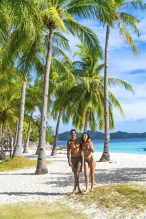 Tourists enjoying their holidays on a beautiful white sand beach surrounded by palm trees on