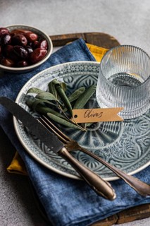 A tasteful arrangement of Greek BBQ olives on a ceramic plate, accompanied by a glass, rustic