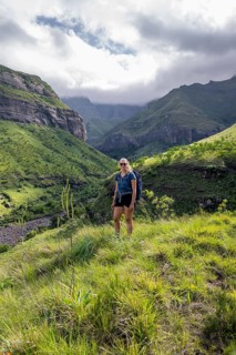 Young female hiker between mountains, Drakensberg National Park, KwaZulu Natal, South Africa
