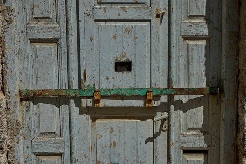 Old blue wooden door with a rusted latch in rustic style, Plaka, main town on Milos, Milos island,