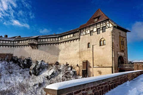 Winter view of a medieval castle with timber frame and snow-covered path in the foreground, The
