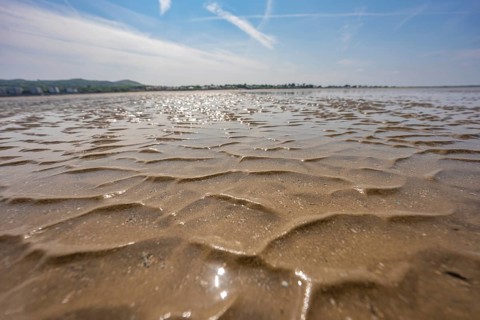 Wide area of wet sand with a wavy pattern under bright sky, low tide, Howth beach, Ireland
