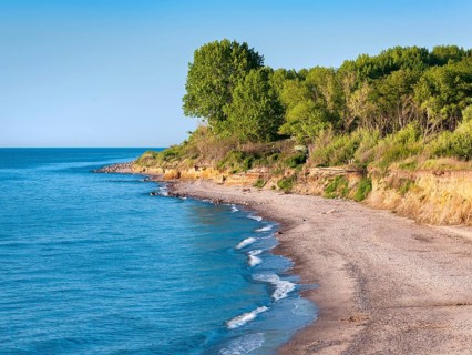 Unspoiled secluded coast of the Baltic Sea with natural beach and cliffs under blue skies in