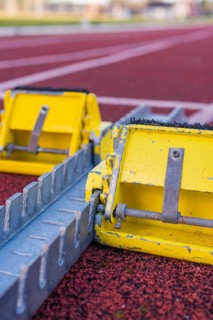 Two yellow starting blocks on a red track, ready for a race