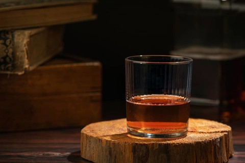 Glass of whiskey on a rustic wooden slice in a cozy atmosphere