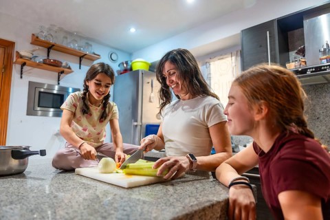 Mother and daughters happily engaging in healthy cooking activities in their kitchen, preparing
