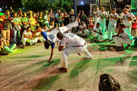 Capoeira artists on the move, accompanied by drumbeats and a large audience, The Capoeira combat