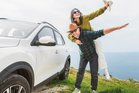 Close up happy couple enjoys holiday time together piggyback ride by their white SUV during