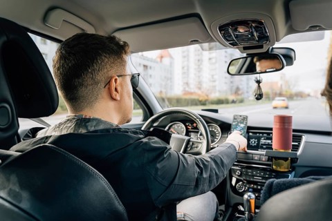 A man uses a phone installed in the holder while driving the car