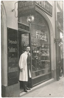 Hairdresser, shop, profession, twenties, hairdresser in traditional clothes stands at the door of a