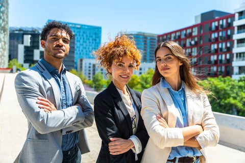 Diverse business people team standing outdoors with crossed arms, looking at camera, representing