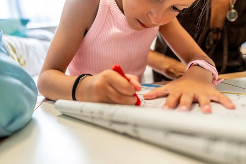 Young girl coloring a drawing on paper, sitting at a table with her grandmother, engaging in