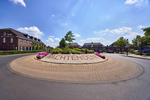 Roundabout, colored concrete paving stones, Wachtendonk lettering, flower bed, road, asphalt,