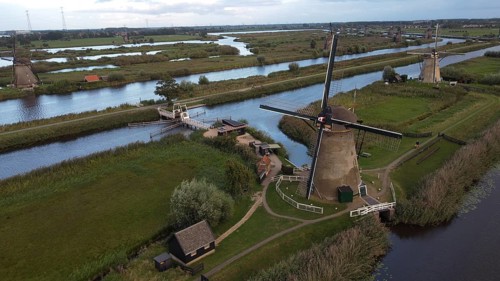 Several windmills along a river in a green landscape with bridges and waterways, windmills along a