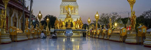 Altar with Buddha statues in front of the chedi decorated with golden ornaments in Wat Phra That