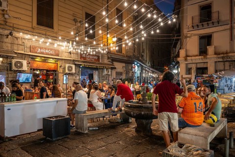 Group of people in a busy square with fountains, fairy lights and restaurants, Palermo, Sicily,