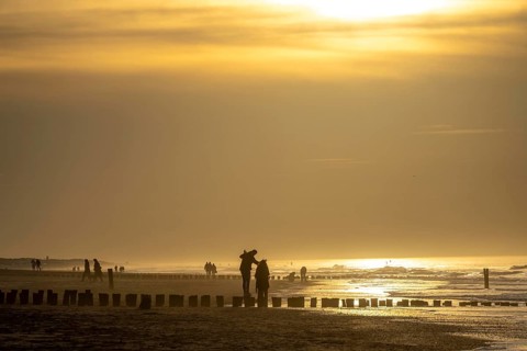 Winter on the North Sea, sunset at sea, beach walkers, coastal protection, through wooden posts,