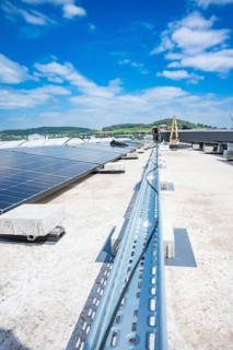 Solar system on roof under blue sky with green landscape in the background, PV installation, Perrot