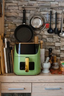 Kitchen countertop with air fryer and various cooking tools like pans and utensils hanging on hooks