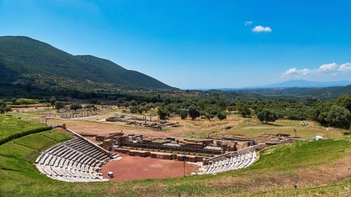 Ancient amphitheatre in a vast, green landscape with mountains in the background, ancient site,