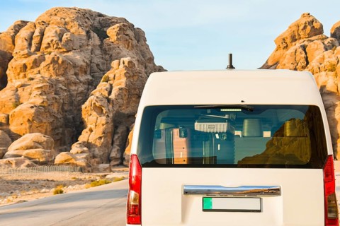 White tourist shuttle minivan full packed rear back view luggage suitcases visible trunk glass