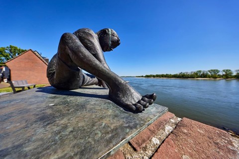Bronze sculpture Friendship connects, boy, sculptor Jürgen Ebert, brick wall, river Rhine, trees,