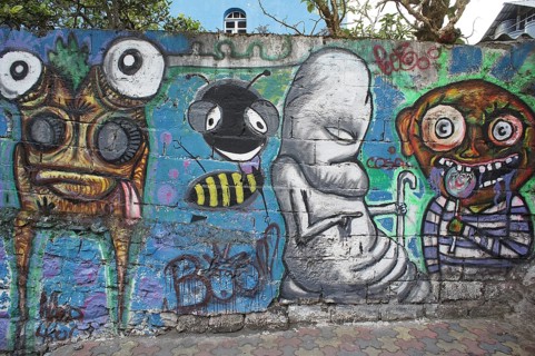 Colorful graffiti with quirky figures and bright colors on a brick wall, Ecuador