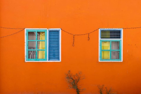 Exterior detail of a bright orange colonial building with colorful wooden shutters in Otrobanda