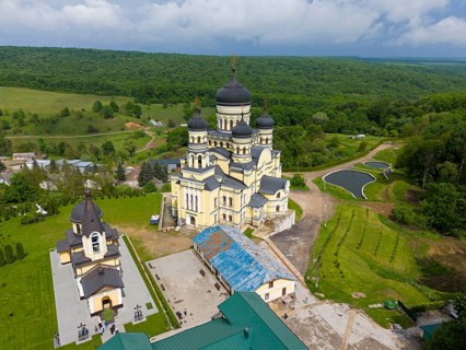 Dome-crowned monastery in vast green countryside and peaceful surroundings, aerial view, Hîncu