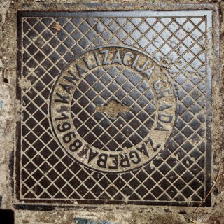 An old metal manhole cover in Zagreb shows a grid pattern, Zagreb, Croatia