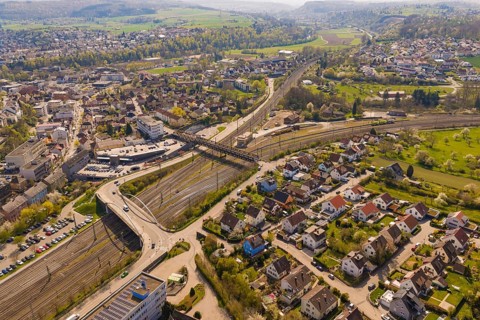 View of a city with branched railway lines and surrounding residential areas in a hilly landscape,