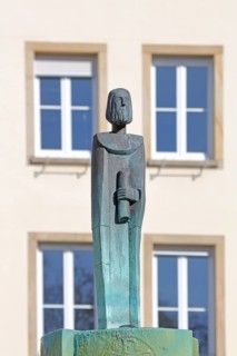 Sculpture at Erkenbert Fountain by Manfred Kieselbach, male figure with scroll, modern art, Town