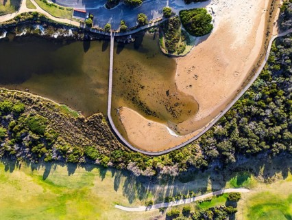 Aerial view of a picturesque coastal landscape featuring green vegetation, a winding waterway and a