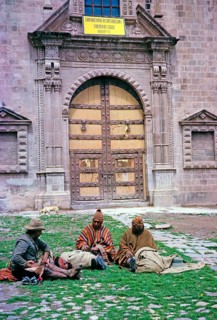 Three indigenous men sitting in front of a historic Spanish colonial building, Cuzco, Peru, South