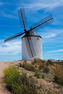 White windmill in a summery, rural landscape on a sandy path with blue sky, Consuegra, Toledo,