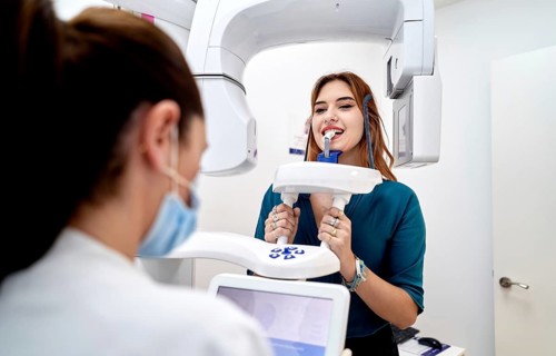 A dentist performs a panoramic dental X-ray on a patient at a modern clinic. The patient is