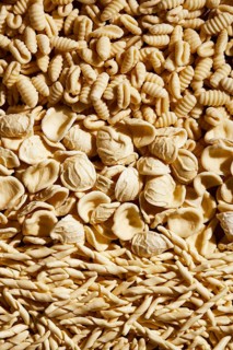 From above, this image showcases a variety of fresh homemade pasta types neatly arranged. The