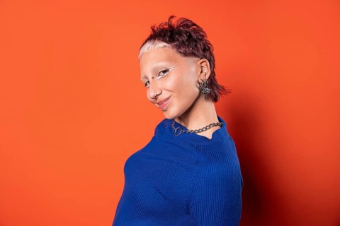 Fashion-forward woman with an edgy hairstyle and bold makeup wearing a vibrant blue outfit against