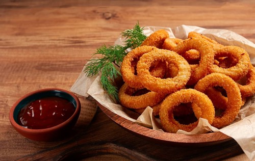 Deep fried onion rings, appetizer, with tomato sauce, on a wooden table, no people, favorite dish