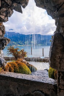 Dramatic view through a rock opening to a waterfall and a lake, St. Beatus Caves, Switzerland