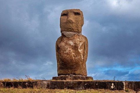 A single moai stands on a stone pedestal surrounded by a dramatic sky, The moai statues on Easter