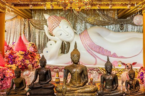 Shrine with reclining Buddha statue, smaller bronze Buddha figures in front of it, Buddhist temple