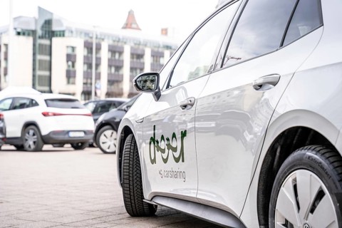 Side close-up of a white carsharing electric car with urban background, Deer, E-Carsharing,