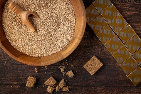 A bowl filled with quinoa next to soup cubes on a wooden table