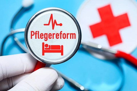 Hand holding stethoscope with inscription care reform, pictogram of a hospital bed and heart curve,